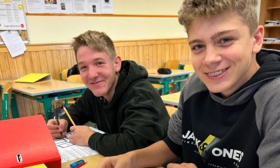 Zwei Schüler lernen gemeinsam die Aufgaben der Landwirtschaft. Sie sitzen in der Klasse und sehen grinsend in die Kamera.